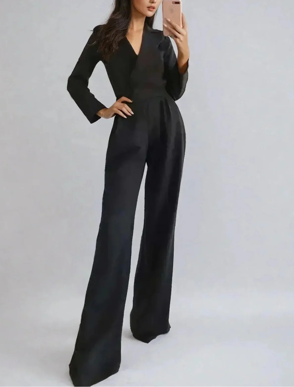 Woman wearing a black jumpsuit against a plain background