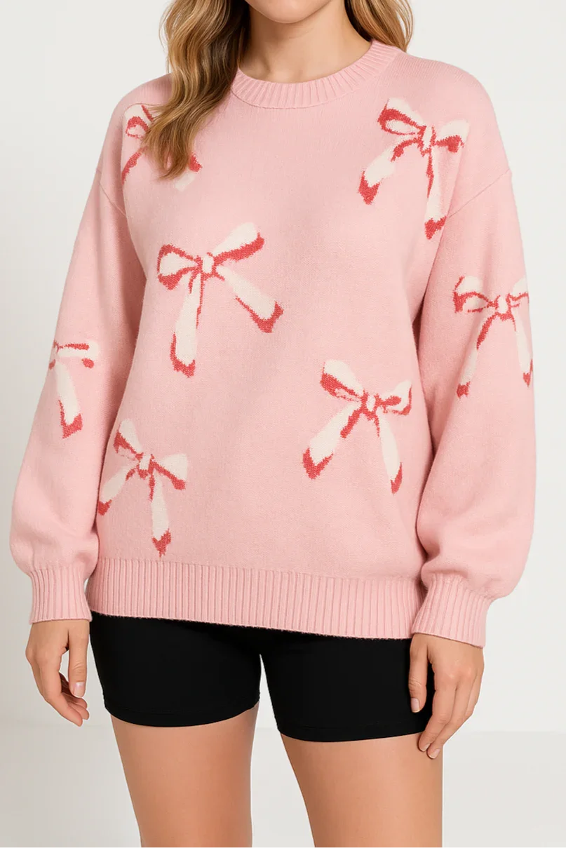 Woman wearing a pink sweater with bow patterns on a plain background