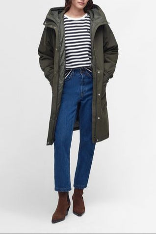 Woman wearing a long green coat, striped shirt, and blue jeans on a white background