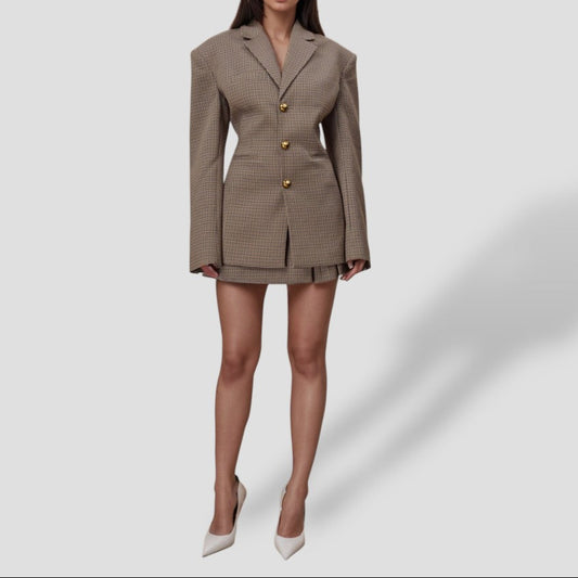 Woman wearing a brown checkered blazer dress with gold buttons on a white background