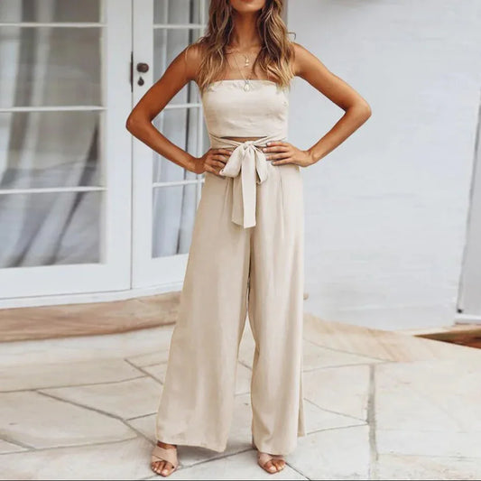 Woman wearing a beige strapless jumpsuit with a belt, standing on a patio.