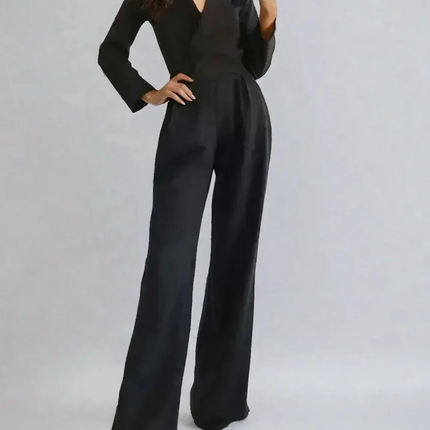 Woman wearing a black jumpsuit against a plain background
