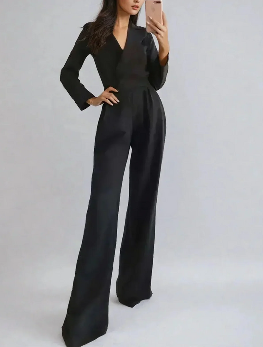 Woman wearing a black jumpsuit against a plain background