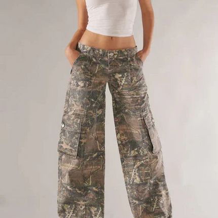 Woman wearing a white tank top and camouflage pants on a plain background