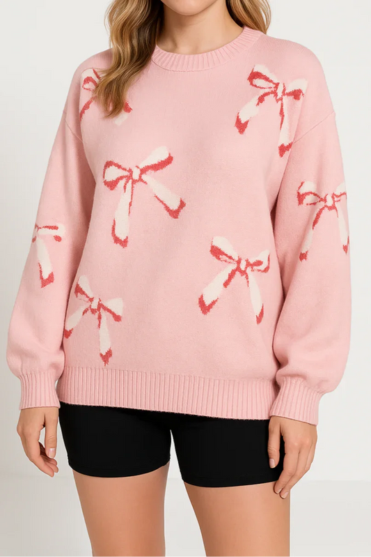 Woman wearing a pink sweater with bow patterns on a plain background