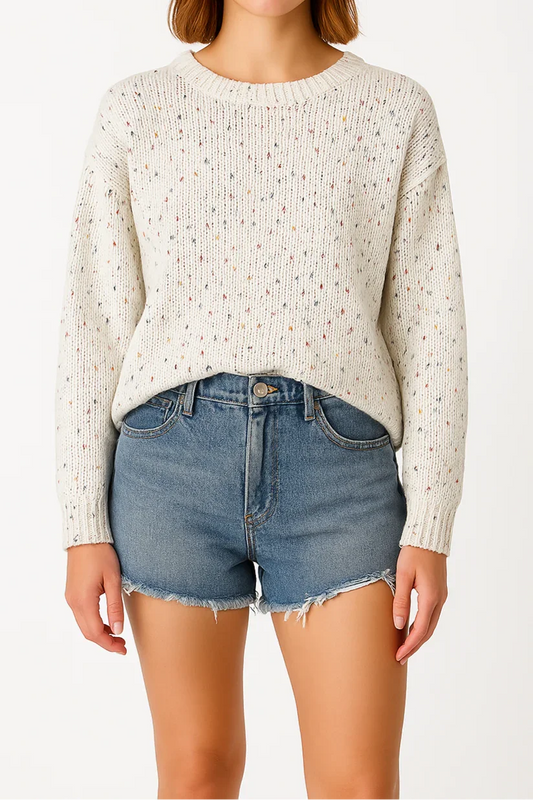 Woman wearing a white textured sweater and blue denim shorts on a white background
