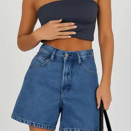 Woman wearing a strapless navy top and denim shorts on a plain background