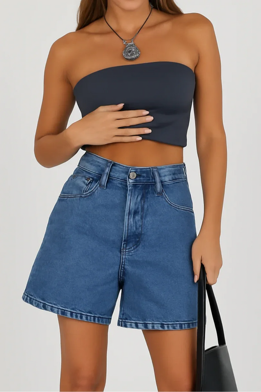 Woman wearing a strapless navy top and denim shorts on a plain background