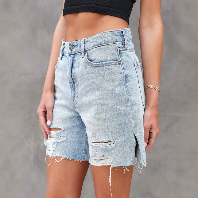 Person wearing distressed denim shorts against a gray background