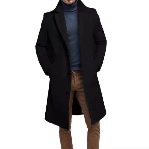 Man wearing a black coat over a blue sweater and brown pants on a white background