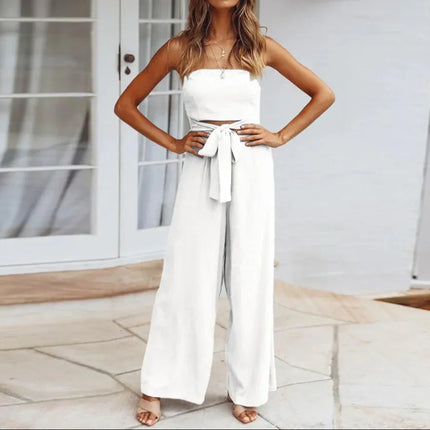 Woman wearing a white strapless top and wide-leg pants standing on a patio.